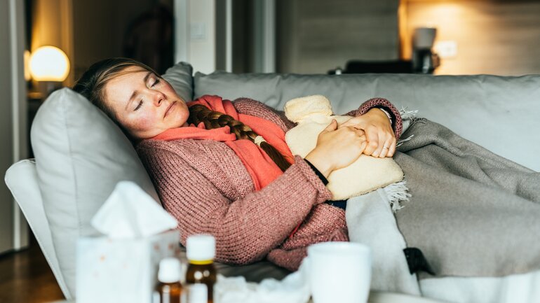 Frau mit Corona-Infektion liegt auf dem Sofa