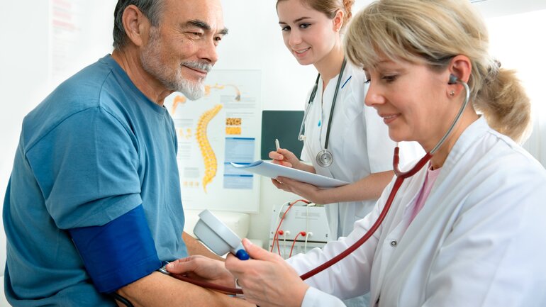 Ärztin misst Blutdruck eines Patienten