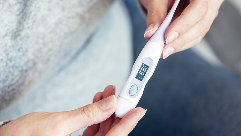 Frau hält Fieberthermometer in der Hand