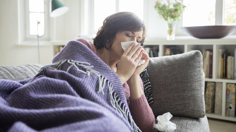 Frau liegt mit Grippe auf dem Sofa