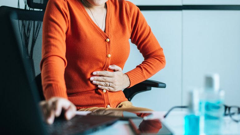 Frau hat Magenkrämpfe im Büro