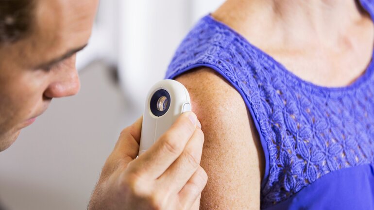 Hautarzt untersucht Haut einer Patientin