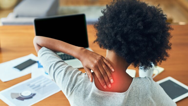 Frau im Home Office mit Nackenschmerzen