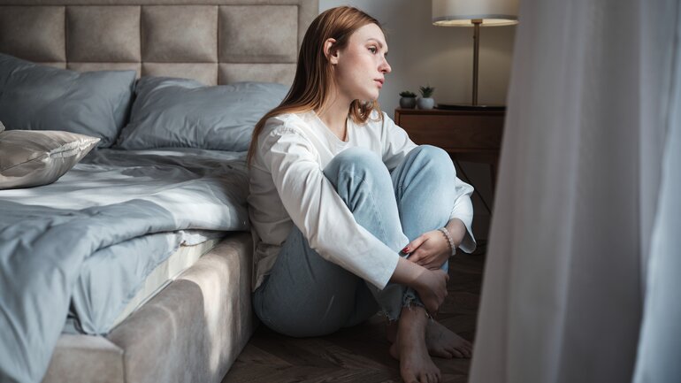 Junge Frau schaut traurig aus dem Fenster
