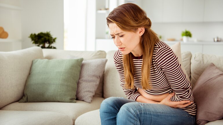 Frau mit Bauchschmerzen auf dem Sofa