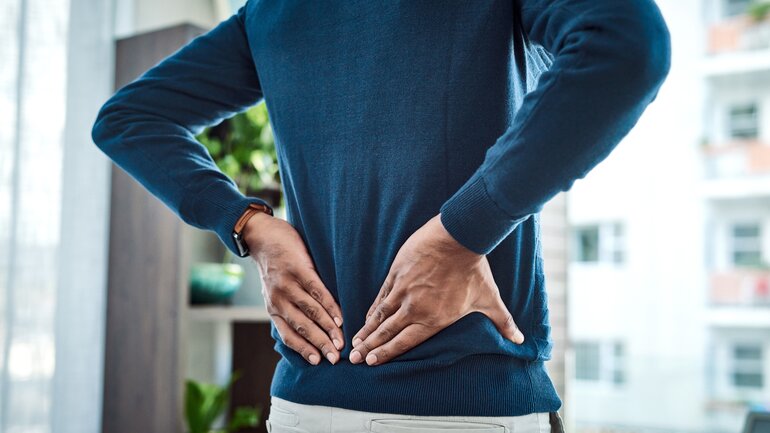 Mann leidet an Sakroiliitis und hat Schmerzen im unteren Rücken.