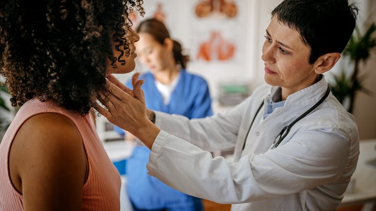 Ärztin tastet Schilddrüse bei Patientin ab