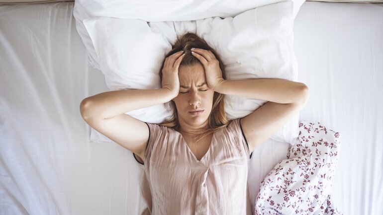 Junge Frau liegt im Bett und leidet unter Schlaflosigkeit