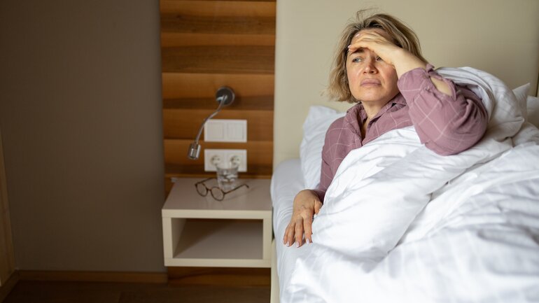 Schlafstörungen in den Wechseljahren: Frau liegt müde im Bett