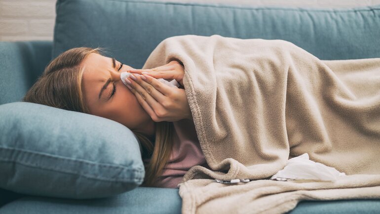 Frau mit Schnupfen liegt auf Sofa