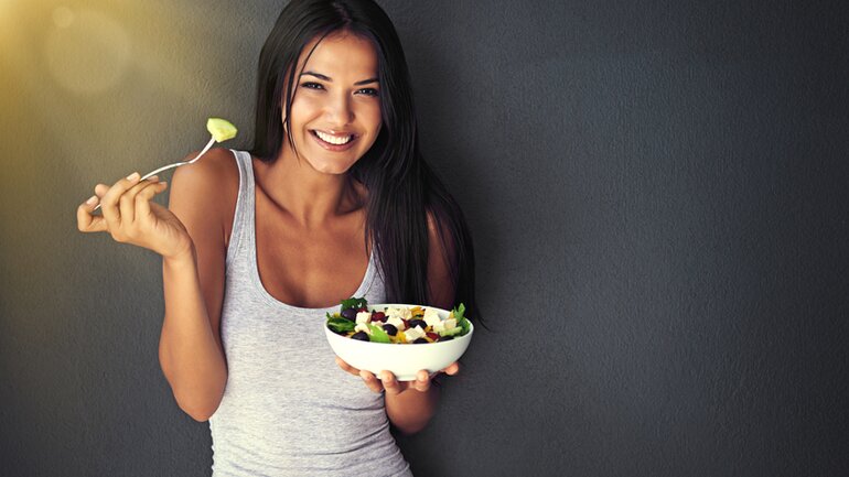 Frau isst Salat und freut sich